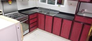 a small kitchen with red cabinets and a sink at Al thabit hotel apartment in Sur