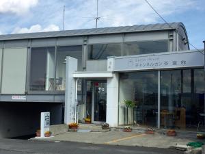een groot glazen gebouw met een bord dat pension leest bij Guesthouse Channel-Kan in Kamojima