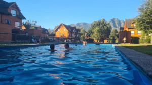 a couple of people swimming in a swimming pool at Casa Tipo Town House in Pucón