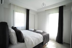 Un dormitorio blanco con una cama y dos ventanas. en MSD Konakları, en Muğla