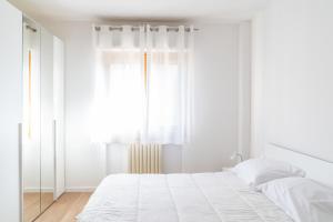 a white bedroom with a bed and a window at Passignano Lake Apartment in Passignano sul Trasimeno