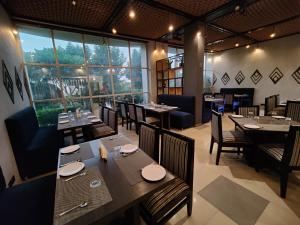 GangānagarHotel Vikramaditya的有木桌椅和窗户的餐厅