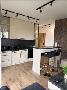 Una cocina con gabinetes blancos y una encimera negra. en Stylowy apartament z ogródkiem i tarasem, en Nysa
