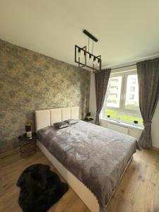 Un dormitorio con una cama grande frente a una ventana. en Stylowy apartament z ogródkiem i tarasem, en Nysa