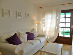 a living room with a white couch and purple pillows at Casa Paola in Tías