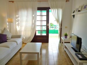 a living room with a white couch and a tv at Casa Paola in Tías