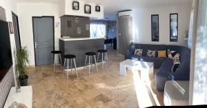 ein Wohnzimmer mit einer blauen Couch und einer Küche in der Unterkunft Villa 200m2, 3 suites, patio avec salle jeux, 1 piscine CHAUFFE DE DEBUT AVRIL A FIN OCTOBRE in Maruéjols