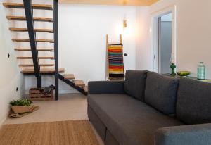 a living room with a couch and a staircase at Ribeira d'ilhas Shelter in Santo Isidoro