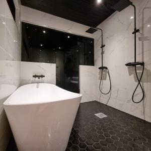 Una bañera blanca en un baño con ducha. en Lapland Villa Ulpukka, en Rovaniemi