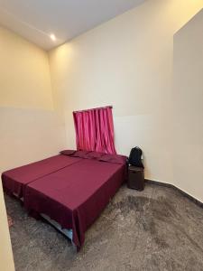 a bedroom with a purple bed with a red curtain at Marigold Homestay - Mysore in Mysore +2 photos