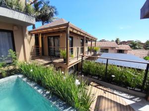 a house with a deck and a swimming pool at Pousada Kirana in Praia do Rosa