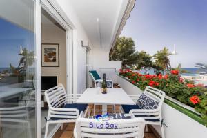 a white table and chairs on a balcony with flowers at Bliss On The Bay Apartment in La Herradura