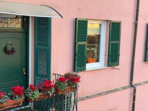 a pink building with green doors and flowers on a balcony at Casa Nina Carignano in Genoa