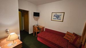 a hotel room with a red couch and a desk at Gasthof Linko in Traisen