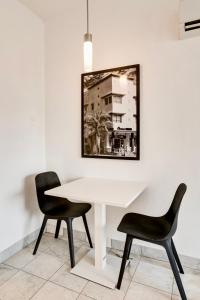 Biały stół z dwoma krzesłami i zdjęciem na ścianie w obiekcie Best location by the Beach ! Free WiFi - TV - All amenities w Miami Beach