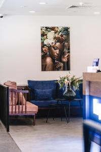 a living room with a blue couch and a painting at Kepler Club Riga Airport Hotel - Landside Public Area in Rīga
