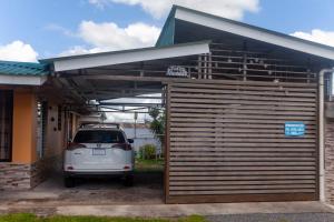 una piccola auto bianca parcheggiata sotto un garage di Apartamento Daly 3 a Guápiles