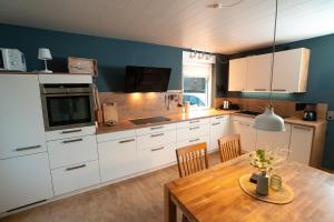 a kitchen with white cabinets and a wooden table at Ferienhaus Glücklich am Harz in Goslar
