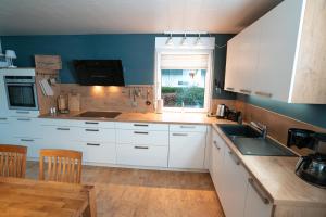 a kitchen with white cabinets and a sink and a window at Ferienhaus Glücklich am Harz in Goslar