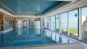 Hotel Strandperle في كوكسهافن: مسبح في بيت بسقوف زرقاء ونوافذ