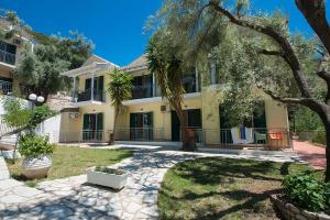 a large yellow house with a tree in the yard at Ilios Hotel & Villas in Yénion