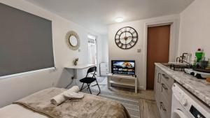 a bedroom with a bed and a tv and a desk at Cozy studio with Netflix & chill & Parking in Ponders End