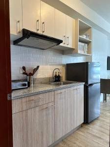a kitchen with a sink and a refrigerator at The Cozy Condo in Bacolod 1208 in Bacolod