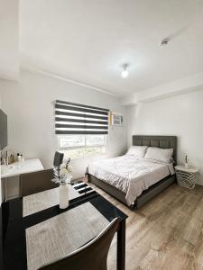 バコロドにあるThe Cozy Condo in Bacolodのベッドとテーブルと窓のある寝室