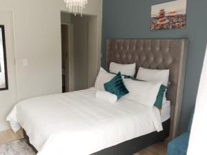 Un dormitorio con una gran cama blanca con almohadas azules. en De Serene B&B, en Midrand