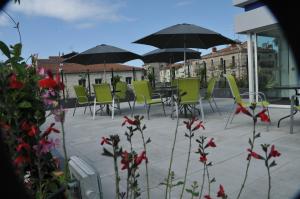 un patio con sillas verdes y mesas con sombrillas en Privilège Hôtel & Apparts Eurociel Centre Comédie, en Montpellier