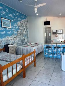 a room with two beds and a table and a kitchen at Pousada Cantinho Azul Qt 01 in Passo de Torres