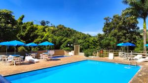 a swimming pool with tables and chairs and umbrellas at Chalés Vila da Serra in Serra Negra