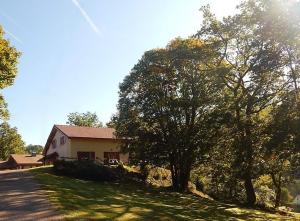 a house with a tree on the side of a road at Chalet de la Rougeterre in Le Ménil
