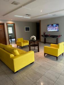 sala de estar con muebles de color amarillo y TV de pantalla plana. en Maravilhoso Flat, en Río de Janeiro