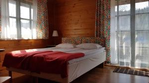 a bed in a room with wooden walls and windows at Leonówka Bieszczady in Cisna