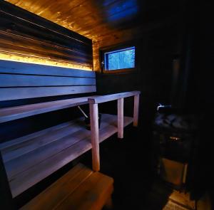 a wooden bench in a room with a window at Beach cottage with sauna in Kajaani