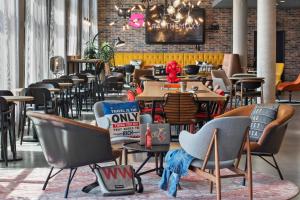 Un restaurante con mesas y sillas y una pared de ladrillos. en Moxy Frankfurt Airport Kelsterbach, en Kelsterbach