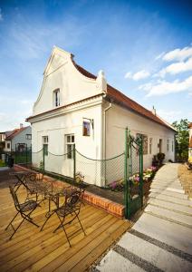 a white building with a green fence on a wooden deck at Café FARA in Klentnice