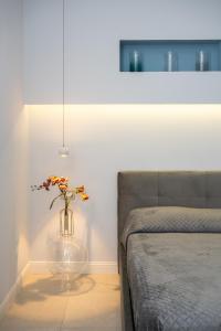 a vase with flowers in it sitting next to a bed at Amnis rooms in Salerno