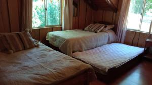 a bedroom with two beds and a window at Cabaña en Parcela con Tinaja in Trancura