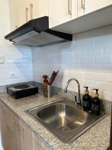 a kitchen counter with a sink and a stove at The Cozy Condo in Bacolod 1208 in Bacolod +34 photos