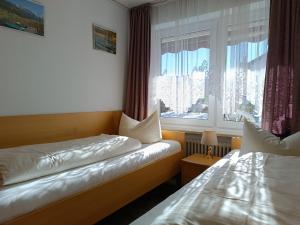 two beds in a small room with a window at 2-Raum FeWo Edelweiß - Hallenbad & Sauna in Fischen +8 photos
