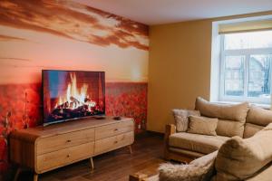 a living room with a tv and a couch at Lovely apartment for families and couples in Liepāja