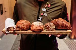 a person holding a tray of croissants and pastries at MOXY NYC Times Square in New York