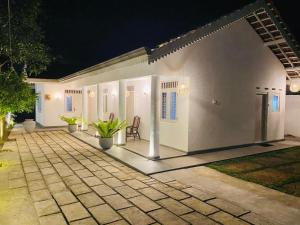 ein weißes Haus mit einer Terrasse in der Nacht in der Unterkunft Havana Weligama Bay in Weligama