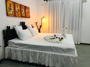 a bedroom with a white bed with a swan on it at Rainforest Mask villa in Deniyaya