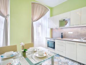 eine Küche mit einem Glastisch und weißen Schränken in der Unterkunft Apartment Ondrejska 20 in Karlsbad