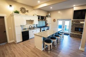 Una cocina con gabinetes blancos y una encimera con taburetes. en Sleeps 40, Pool House, en Garden City