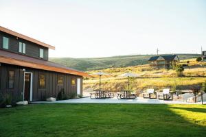 Un patio con mesas y sombrillas al lado de una casa. en Sleeps 40, Pool House, en Garden City