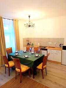 a kitchen with a table with chairs and a green table cloth at 2 room's Family Apartments Mürzzuschlag in Mürzzuschlag